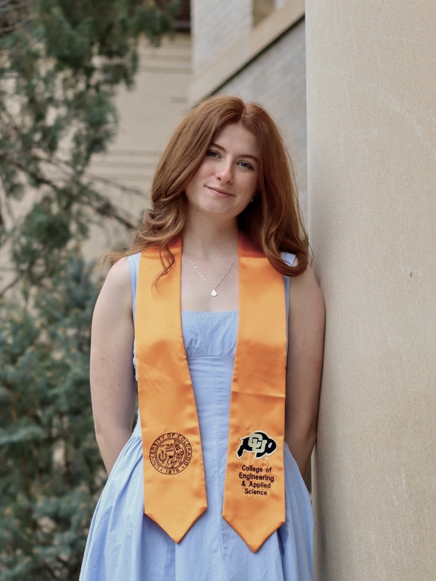 A photo of Ragan Lee. She is a 22 year old woman with red hair and blue eyes. She is wearing a blue dress and an orange graduation stole.